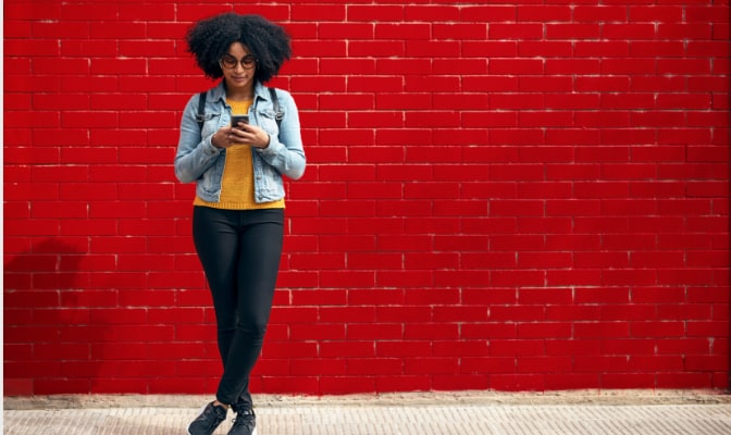 Woman standing against a wall and looking at her mobile phone